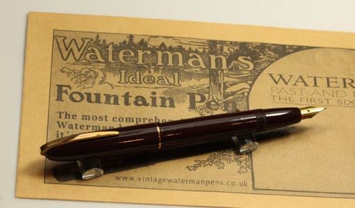 A fountain pen sitting on top of a newspaper.